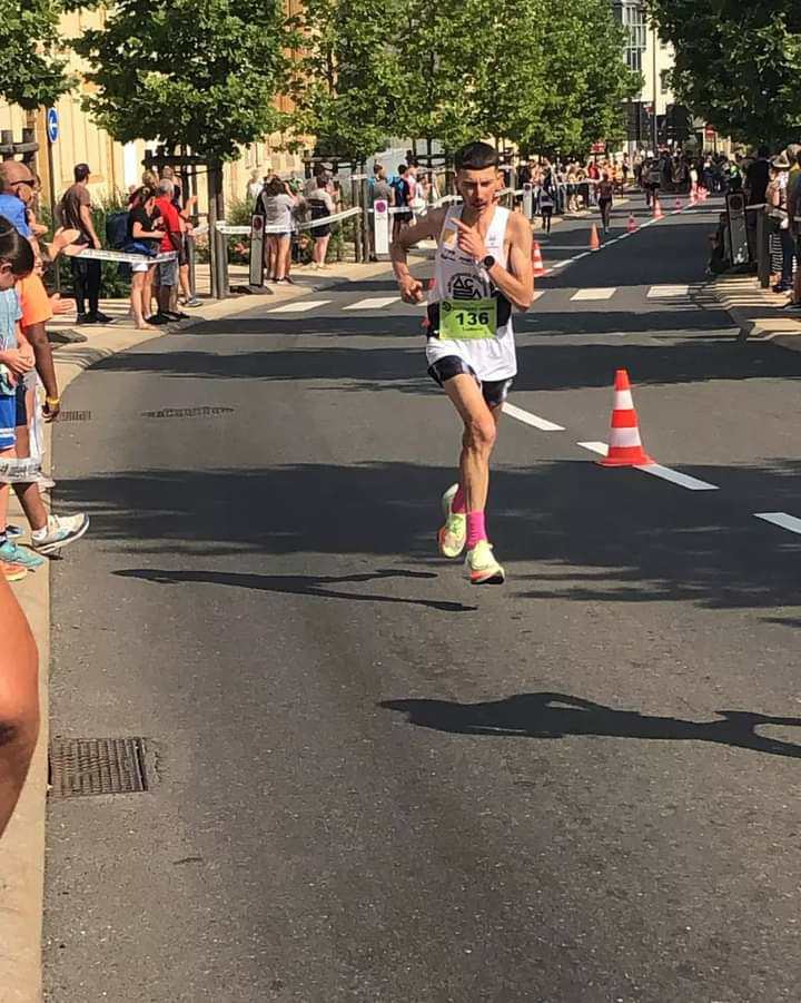 Ludovic Delpuech en course sur route bordée d'arbres, dossard 136