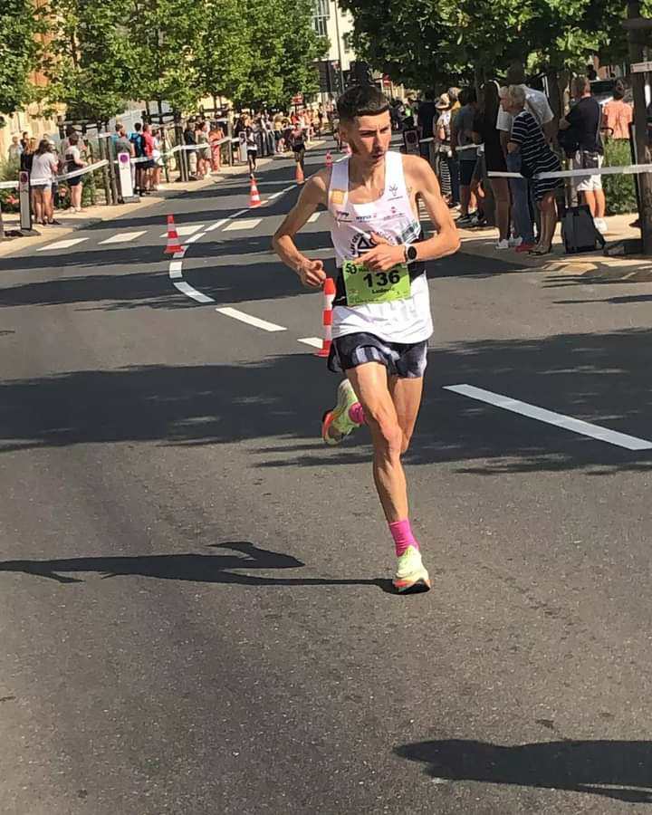 Ludovic Delpuech en course sur route en ville l'été, dossard 136